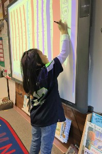 Vaughan's student writes on a smartboard