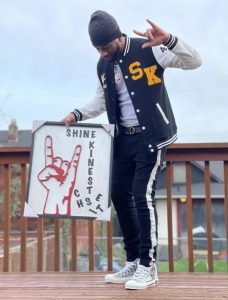 CityU Alum holding a sign that says shine kinesthetics, a tutoring business he started after graduating with his MBA