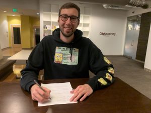 international student sitting with paper, smiling