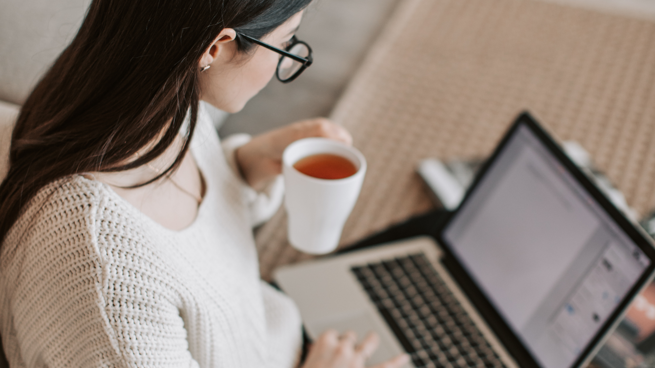 woman starting a resume document on laptop with cup of tea
