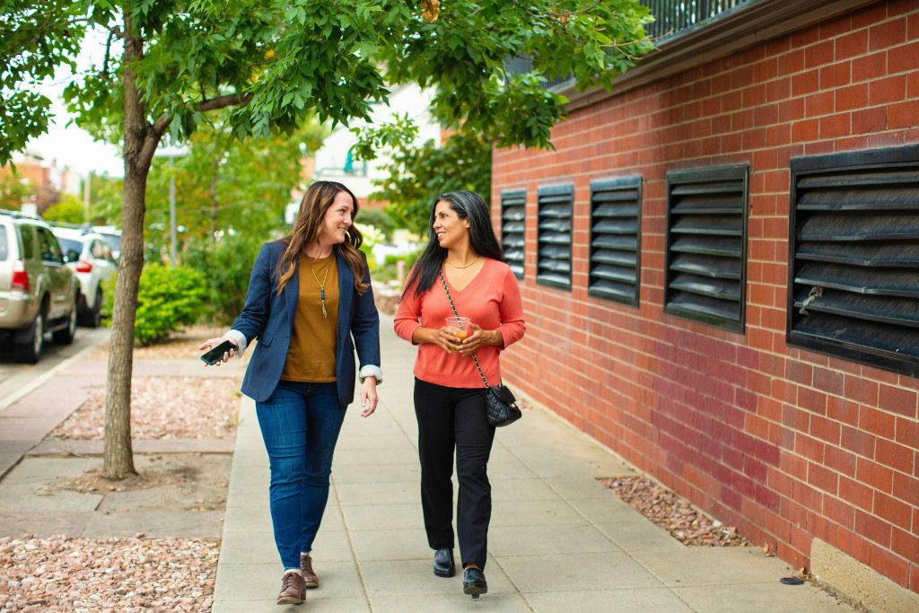 Two women walking and talking on a sidewalk. Leadership and management are one of the top skills 2025.