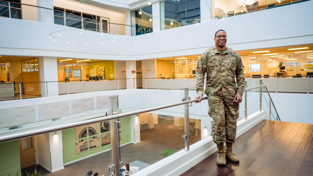 Military student standing in upstairs portion of CityU of Seattle main campus library in military uniform.