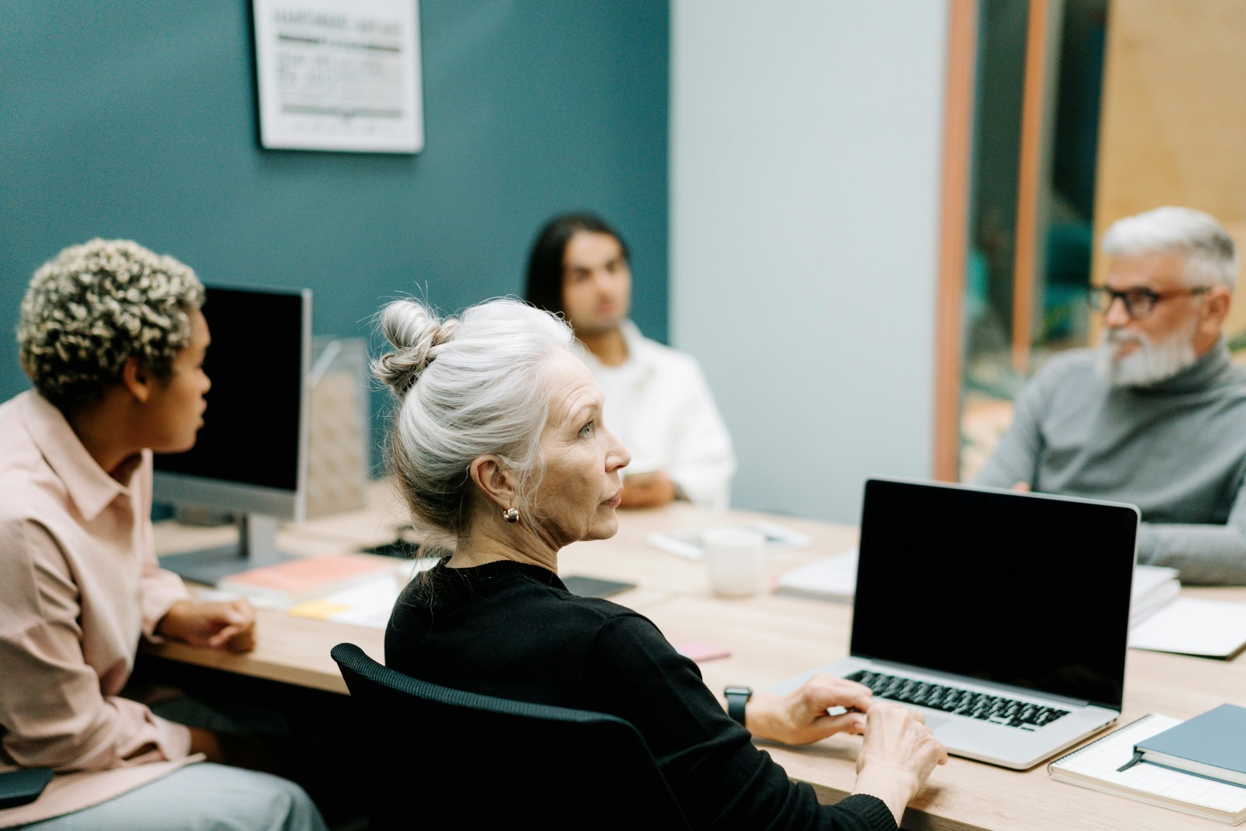business people in a meeting with their laptops, varying in age and other demographics